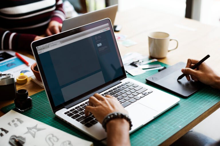 Creative workspace with a laptop, tablet, and design tools.